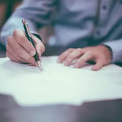 Ręka pisze długopisem na dokumencie. To może być umowa przedwstępna bez notariusza wzór.