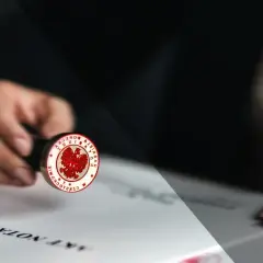Notariusz stempluje dokument, potwierdzając akt poświadczenia dziedziczenia.