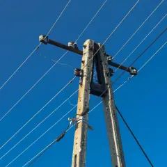 Betonowy słup energetyczny z przewodami pod błękitnym niebem. Zastanawiasz się, ile wynosi odszkodowanie za słupy energetyczne na działce?