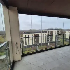 Szklane balustrady i zadaszenie to świetny sposób, jak osłonić balkon przed wiatrem i deszczem, zapewniając komfortowy widok na nowoczesne budynki.