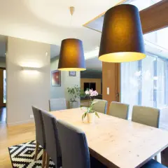 Nowoczesna jadalnia z drewnianym stołem i szarymi krzesłami. To przykład, jak home staging co to znaczy – tworzy przytulną atmosferę.