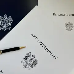 Na stole leży długopis obok dokumentu z napisem "AKT NOTARIALNY" i godłem Polski.