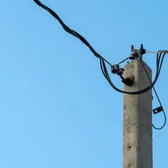 Betonowy słup na działce, który stoi tam od ponad 30 lat, trzymając kable energetyczne.