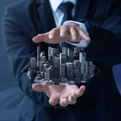 Biznesmen trzyma w dłoniach futurystyczne miasto, symbolizujące inwestycje w nieruchomości i rozwój reit.