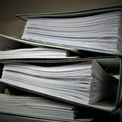 Stosy segregatorów z dokumentami. Szukasz informacji, jak znaleźć numer księgi wieczystej?