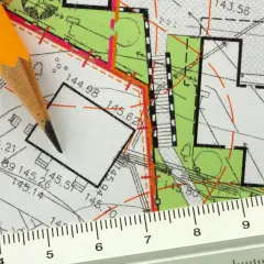 Ołówek i linijka na mapie geodezyjnej. Plan działki z wymiarami, pomocny, by sprawdzić kto jest właścicielem działki.