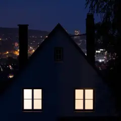 Nocny krajobraz miasta z oświetlonymi domami i budynkami. Immisja światła z miasta tworzy ciepłą poświatę.