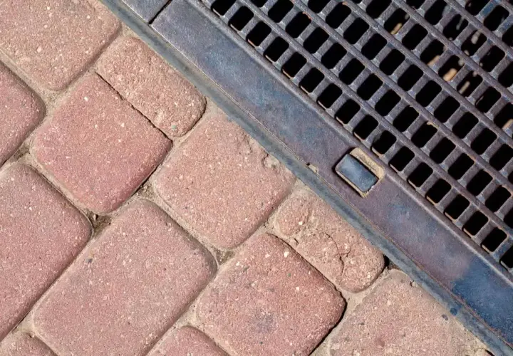 Kostka brukowa i metalowa kratka ściekowa zapewniające sprawne odwodnienie domu.