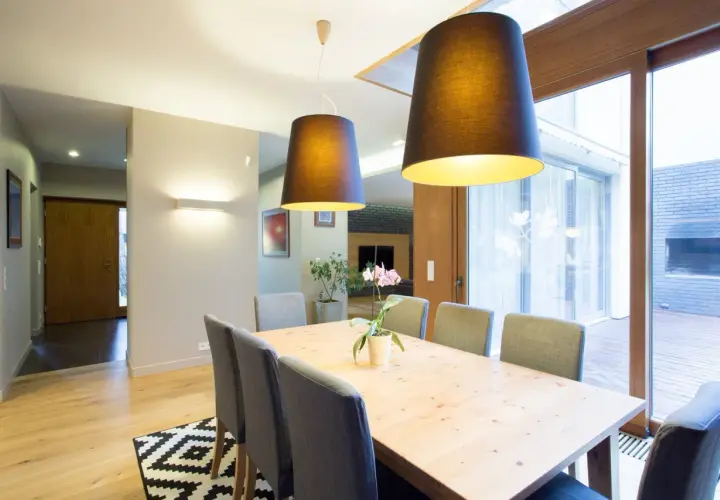 Nowoczesna jadalnia z drewnianym stołem i szarymi krzesłami. To przykład, jak home staging co to znaczy – tworzy przytulną atmosferę.
