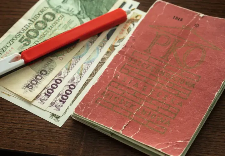 Książeczka mieszkaniowa z PRL-u, banknoty 5000 i 1000 zł oraz czerwony długopis.