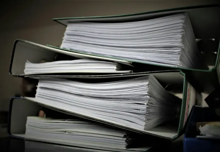 Stosy segregatorów z dokumentami. Szukasz informacji, jak znaleźć numer księgi wieczystej?