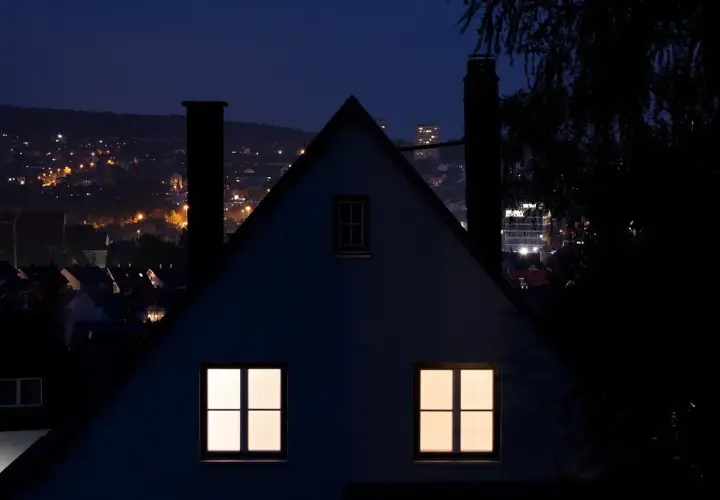 Nocny krajobraz miasta z oświetlonymi domami i budynkami. Immisja światła z miasta tworzy ciepłą poświatę.