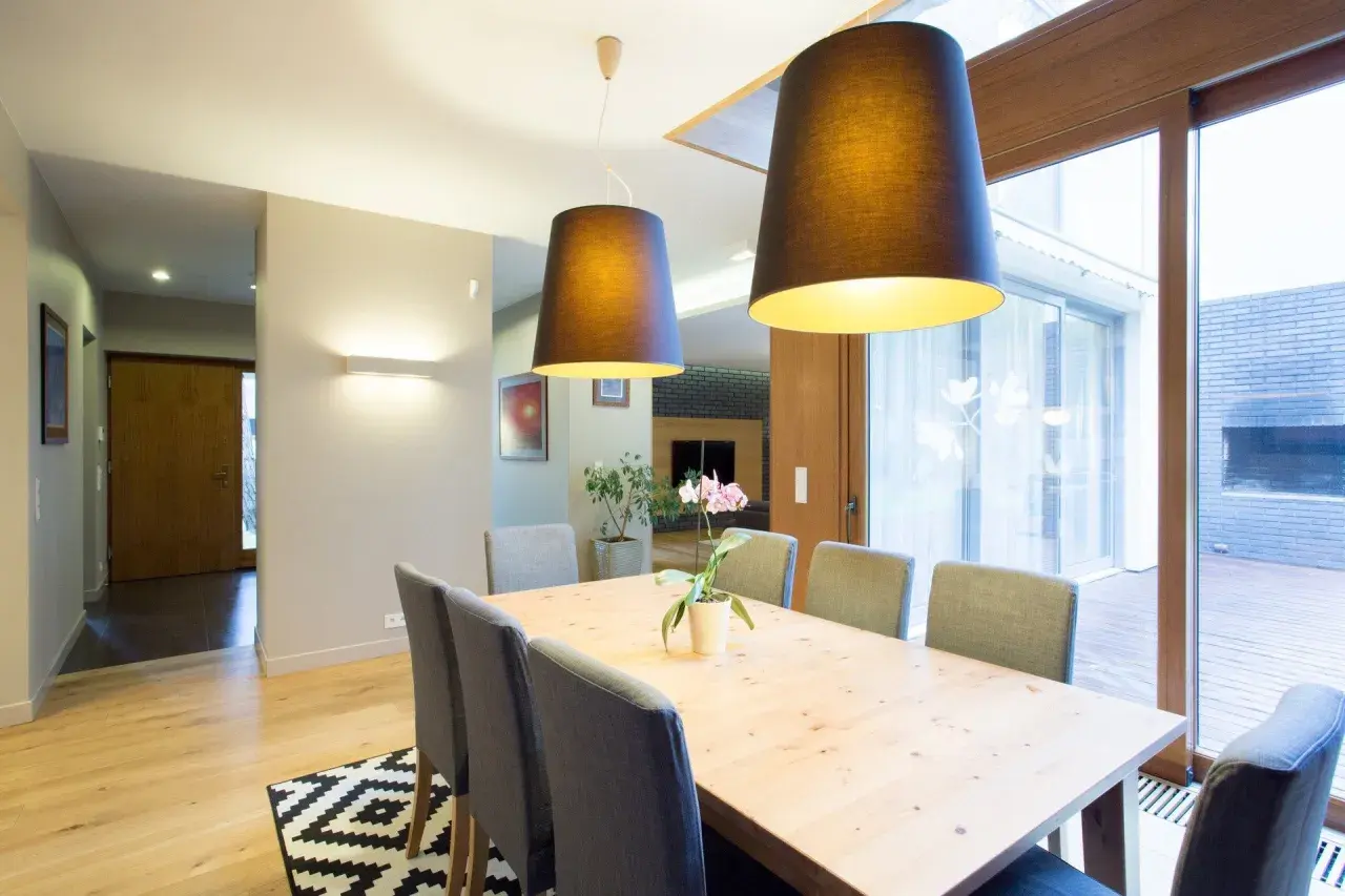 Nowoczesna jadalnia z drewnianym stołem i szarymi krzesłami. To przykład, jak home staging co to znaczy – tworzy przytulną atmosferę.