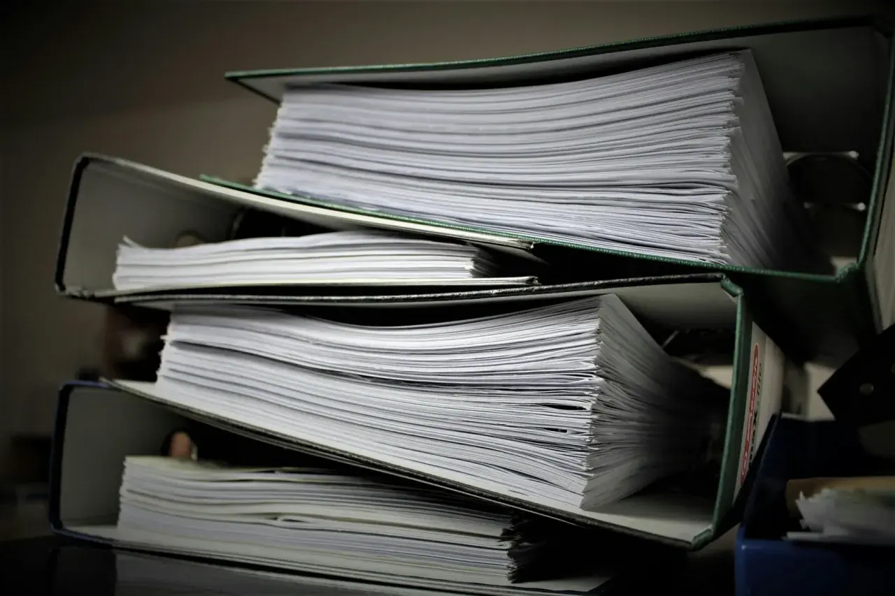 Stosy segregatorów z dokumentami. Szukasz informacji, jak znaleźć numer księgi wieczystej?