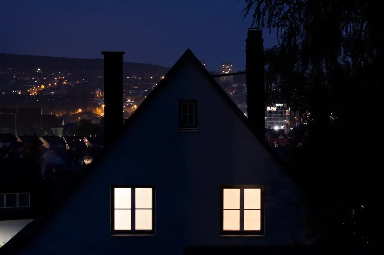 Nocny krajobraz miasta z oświetlonymi domami i budynkami. Immisja światła z miasta tworzy ciepłą poświatę.