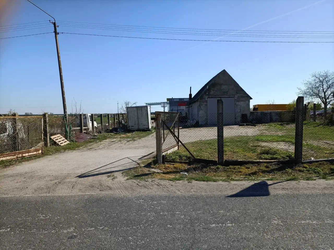 Budynek gospodarczy do 35m2 bez zgłoszenia, z szarym dachem i dwoma drzwiami, otoczony siatką.