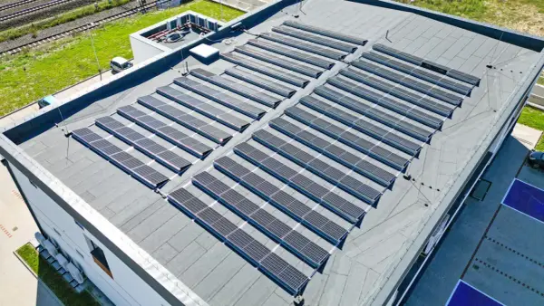 Nowoczesny dom z płaskim dachem pokryty rzędami paneli słonecznych, które czerpią energię ze słońca.